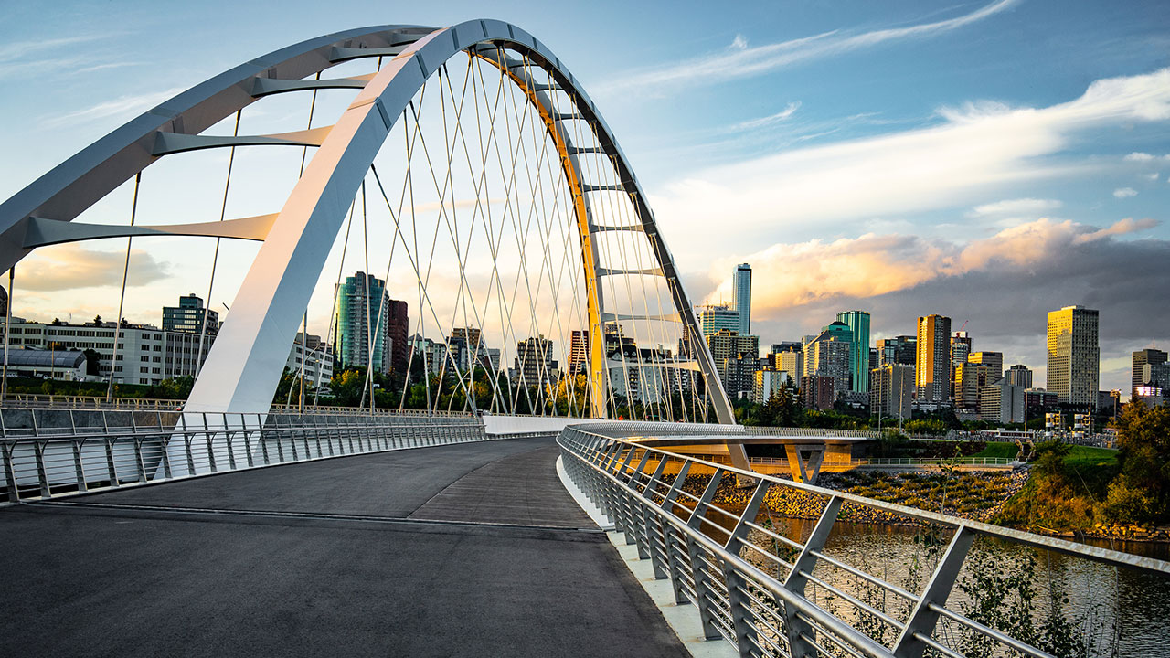 Edmonton, Alberta skyline at dusk with suspension bridge in foreground
